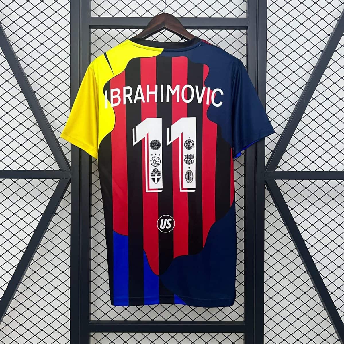 Colorful football jersey hung on a wooden hanger, featuring red and black vertical stripes and yellow left sleeve, with blue on the right.