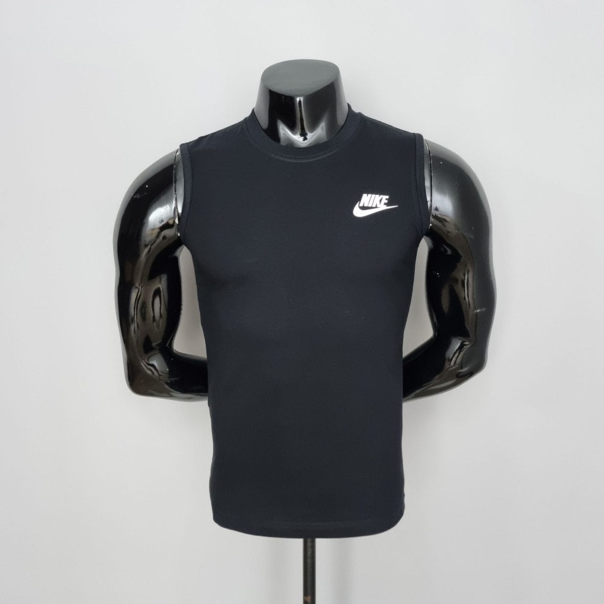 Black Nike sleeveless athletic top on a glossy black mannequin torso against a light gray background, front view.