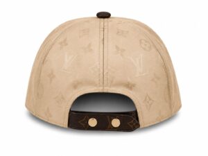 Back view of a beige Louis Vuitton cap with an adjustable strap and gold-tone studs, showing the LV monogram pattern.