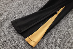 Black jacket sleeve unzipped to reveal mustard-yellow lining and a visible tear at the bottom on a gray carpet surface.