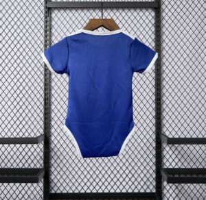 Blue infant onesie with white trim hanging on a wooden hanger against a metal mesh display backdrop
