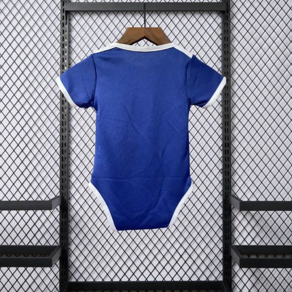 Blue infant onesie with white trim hanging on a wooden hanger against a metal mesh display backdrop