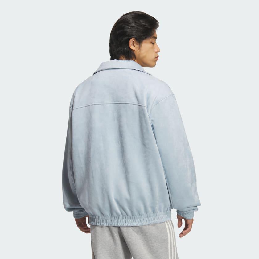 8562a4d9-86e4-41f3-ab98-4a3c6ee47594 | UAE SPORT STORE Person seen from behind wearing a light blue oversized jacket and gray sweatpants, standing against a pale background.