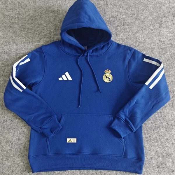 Blue Real Madrid hoodie with hood, features club crest and Adidas logo, white sleeve stripes, and a front pocket on a gray background.