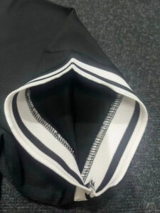 Close-up of a black hoodie hood with wide white and navy striped trim along the edge.