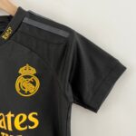 Close-up of a black polo with a gold Real Madrid crest embroidered on the chest.
