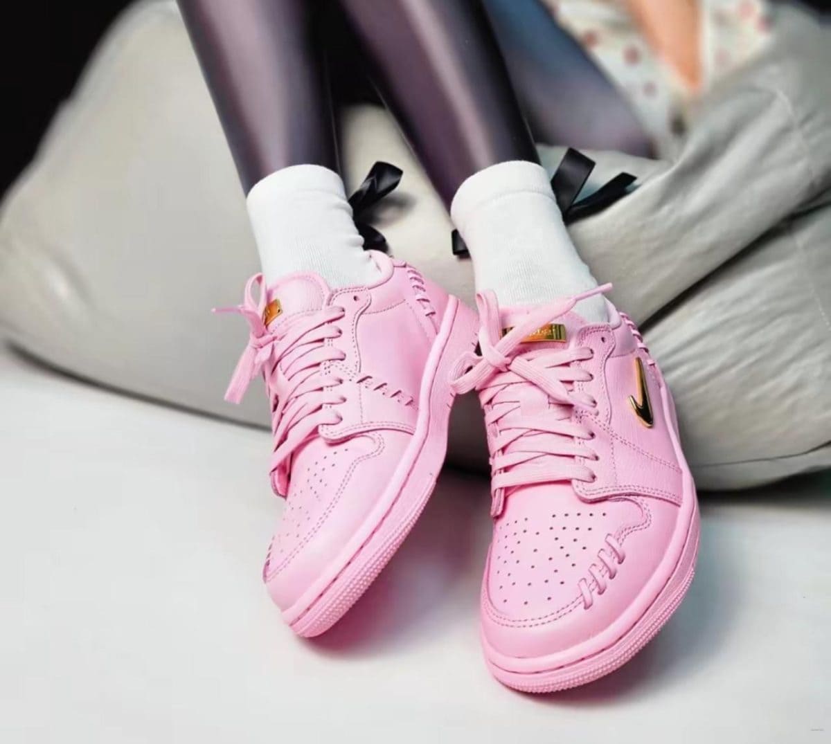 Pair of pink sneakers with white socks resting on a light-colored sofa or chair cushion.