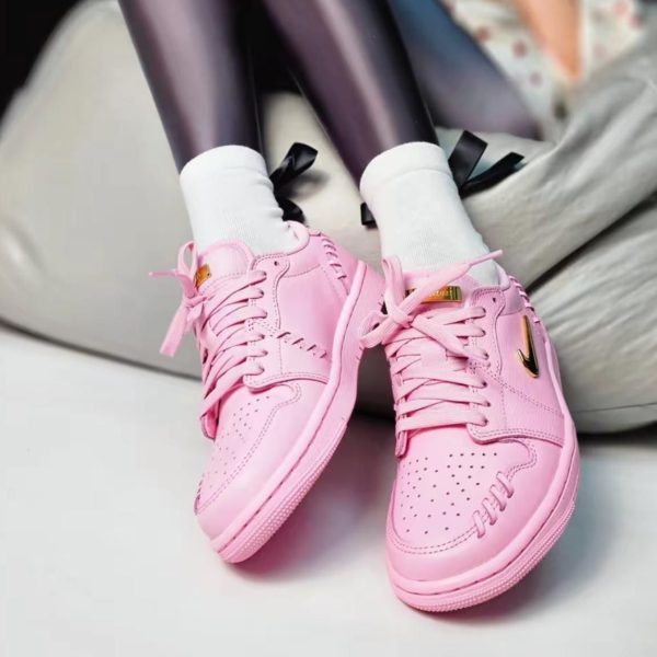 Pair of pink sneakers with white socks resting on a light-colored sofa or chair cushion.