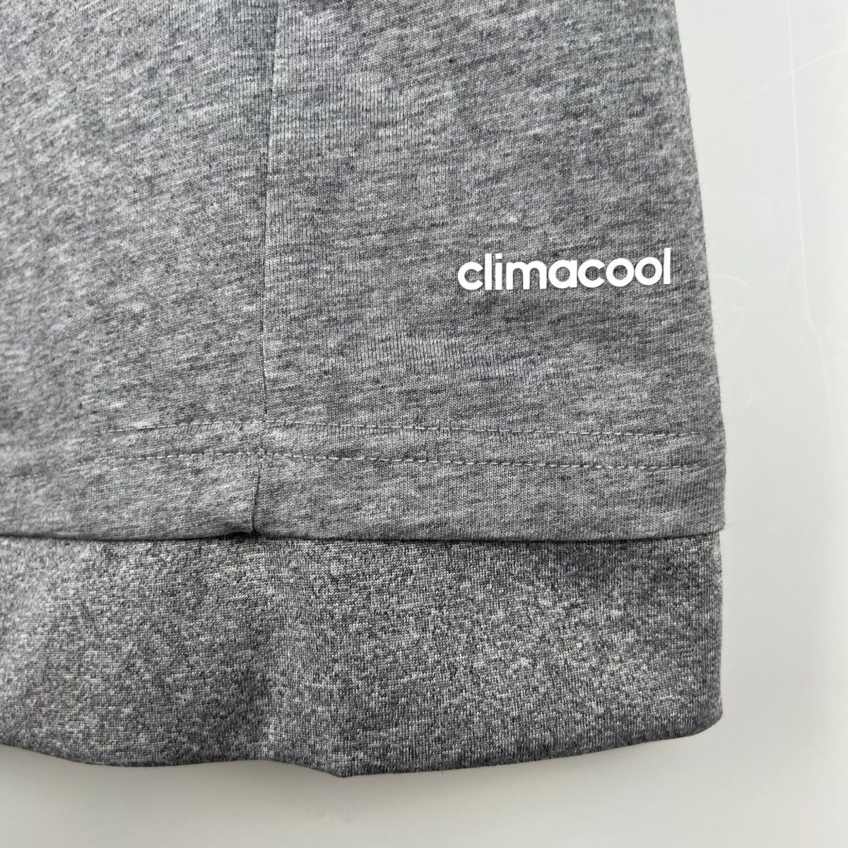 Close-up of heather gray knit fabric with a vertical seam and a partial 'climacool' logo at the edge.