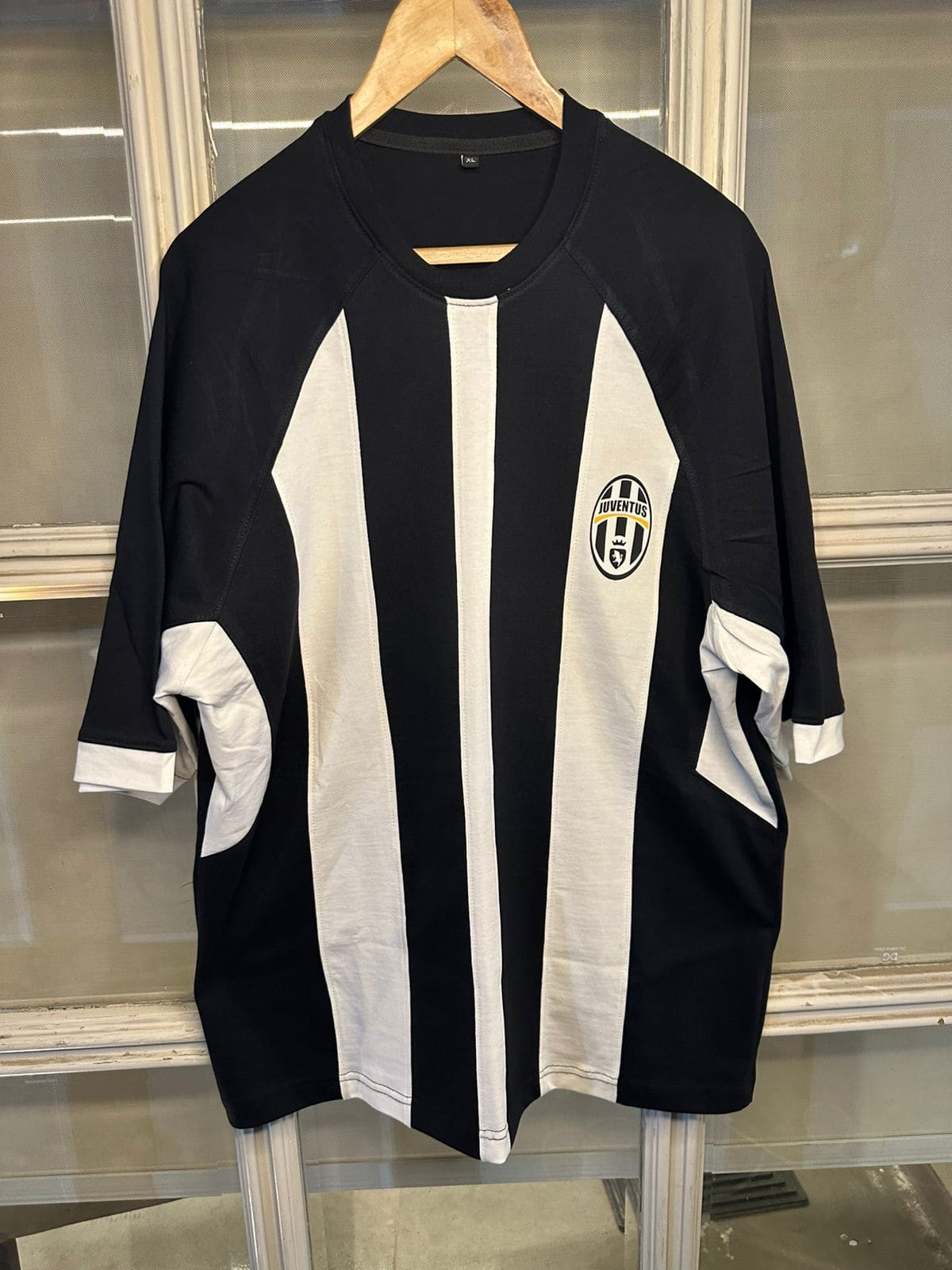 876b4028-c693-410b-b861-3397873b0067 | UAE SPORT STORE Black and white Juventus soccer jersey on a hanger, featuring bold vertical stripes and the crest on the left chest.