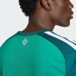 Back view of a person wearing a green athletic jersey with white stripes and a small white logo on the upper back.
