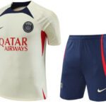 Paris Saint‑Germain soccer jersey and matching shorts: cream jersey with navy and red accents, PSG crest, Qatar Airways sponsor, and navy shorts with a red stripe.