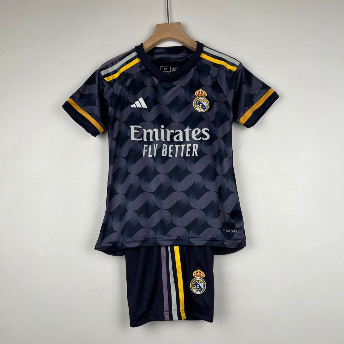 Real Madrid soccer jersey hanging on a wooden hanger, dark navy with Emirates sponsor and crest visible.