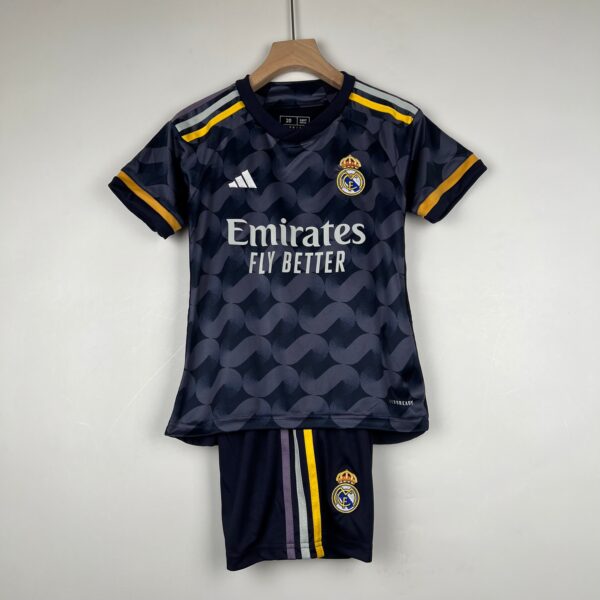 Real Madrid soccer jersey hanging on a wooden hanger, dark navy with Emirates sponsor and crest visible.