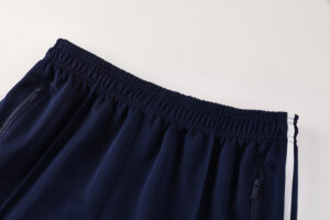 Navy athletic pants with an elastic waistband and zippered pockets, featuring white side stripes along the legs.