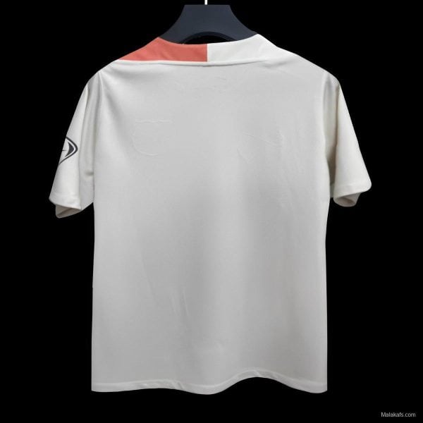 Back view of a white polo shirt on a hanger with a coral collar accent and a partial logo on the left sleeve, against a black background.