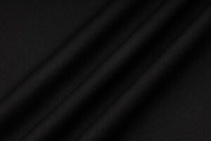 Close-up of black fabric with soft diagonal folds and a fine weave texture