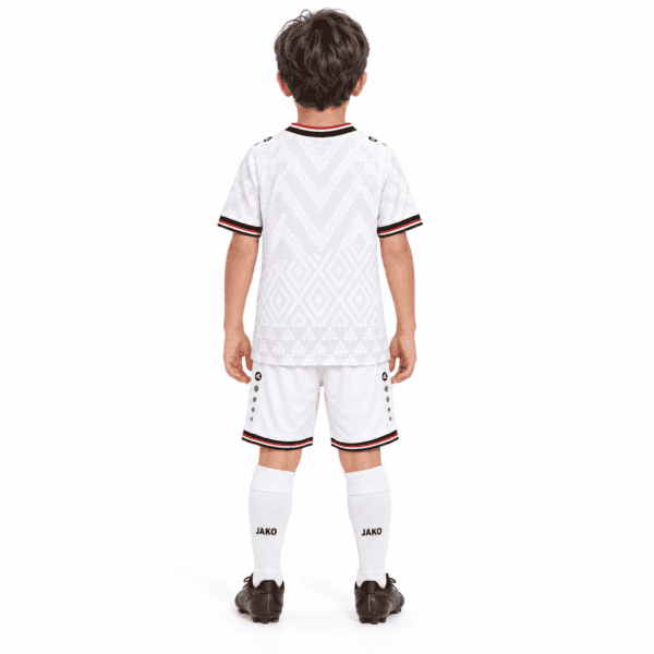 Child in Iraq home kids football kit, white with black and red accents.