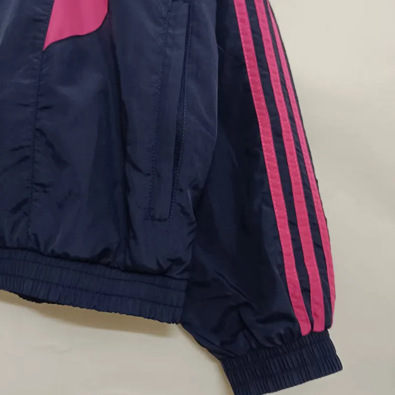 8943f3b19338a8c0 | UAE SPORT STORE Navy windbreaker with pink stripes along the sleeve and a zippered pocket on the side wrist area.