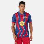 Male model wearing FC Barcelona home football kit (blue and red striped jersey with Spotify sponsor) and red shorts, facing forward.