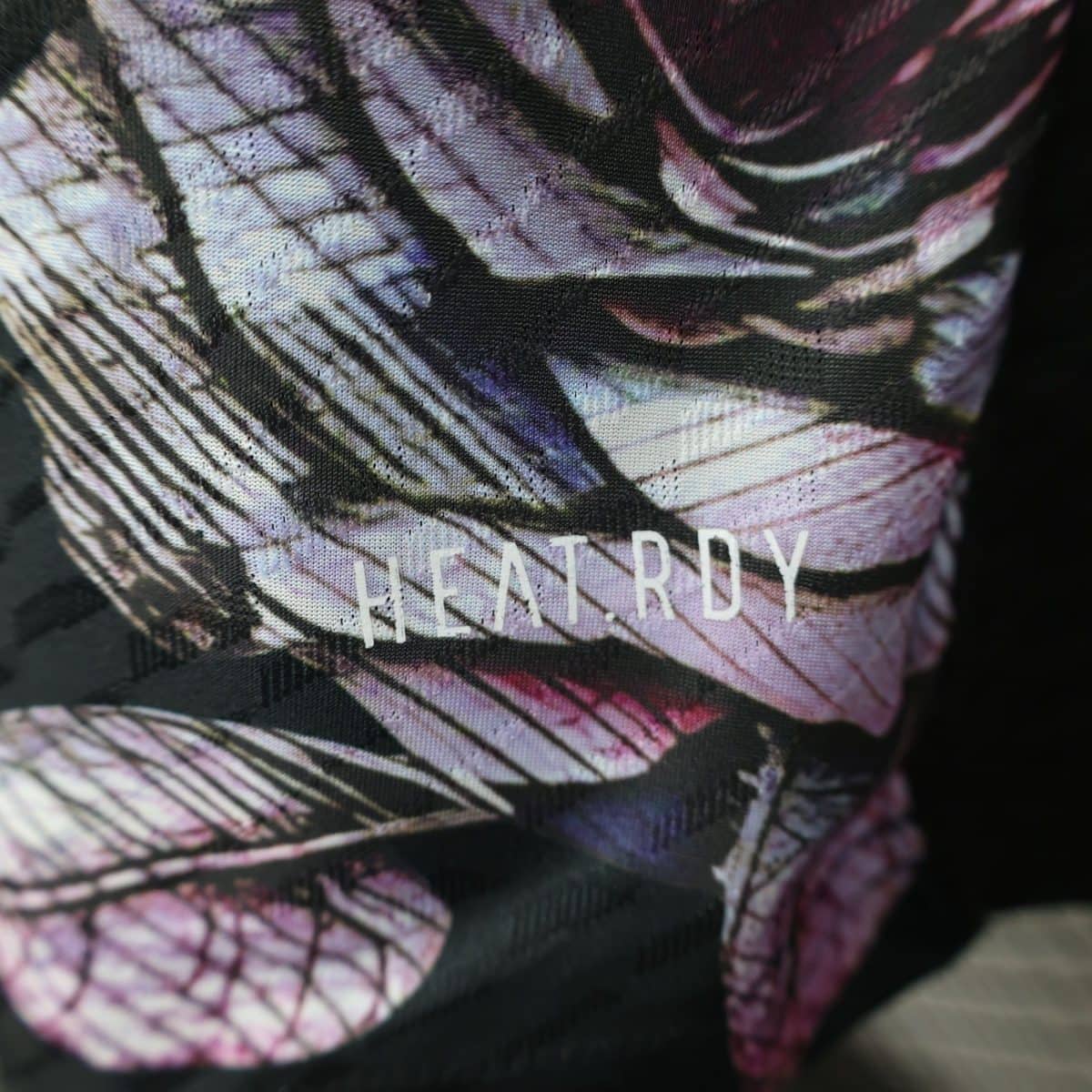 Close-up of patterned fabric with purple and pink lines and a dark background, showing woven texture.