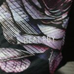 Close-up of patterned fabric with purple and pink lines and a dark background, showing woven texture.
