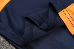 Close-up of navy blue fabric with an orange seam and folded edge.