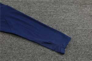 Blue long-sleeve shirt sleeve laid flat on a gray carpet.