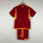 Back view of a maroon sports jersey with orange side panels and trim, hanging on a wooden hanger.