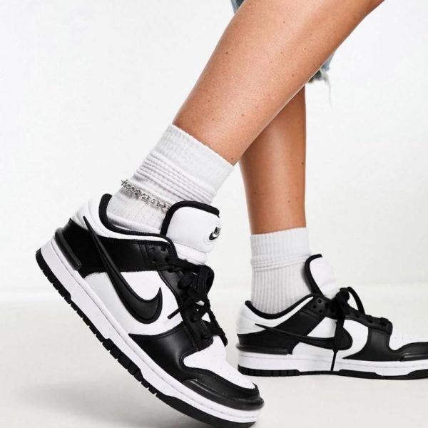 Close-up of feet in white crew socks wearing black-and-white Nike sneakers on a light floor; mid-step pose.