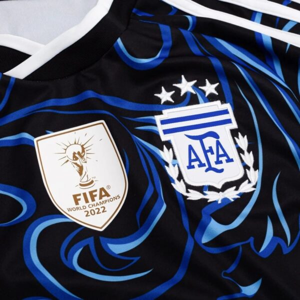 Close-up of a black sports jersey with vivid blue curved stripes and white trim, featuring a FIFA World Champions 2022 badge.