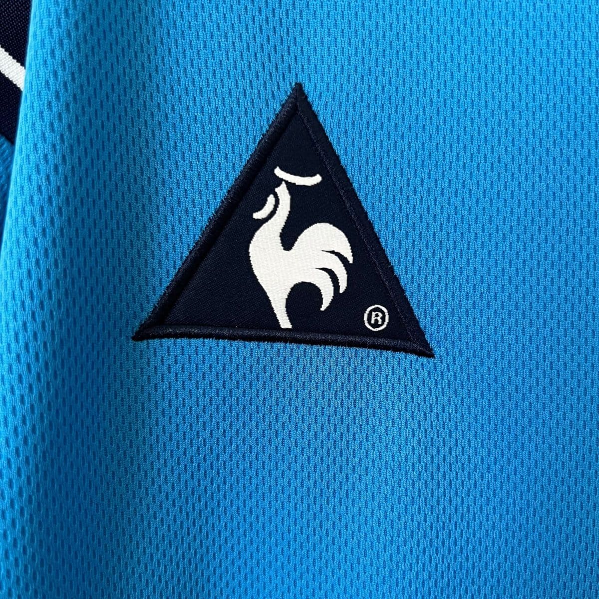 Close-up of bright blue textured fabric with a black triangular patch featuring a white curved design.