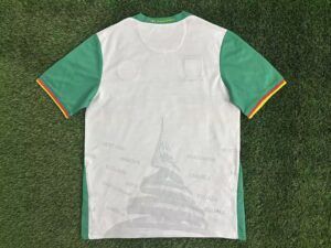 Light green-sleeved white polo or jersey with a green collar; collar reads 'Paix, Travail Patrie'.