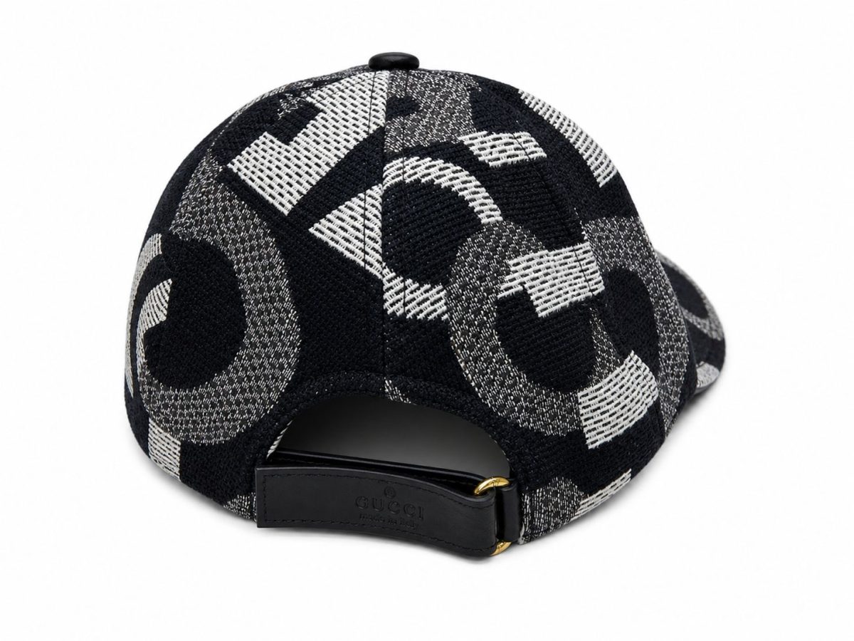 Back view of a black-and-white geometric patterned baseball cap with a leather strap and gold buckle, Gucci branding visible on the strap