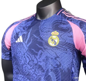 Blue Real Madrid football jersey on a display mannequin, dragon pattern with pink sleeve accents, Real Madrid crest and Adidas logo visible on chest.