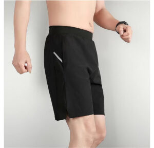 Man wearing black athletic shorts with a zippered side pocket, shown from mid-torso to knees against a light background.