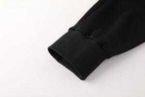 Close-up of a black fabric sleeve cuff with a stitched edge against a light background