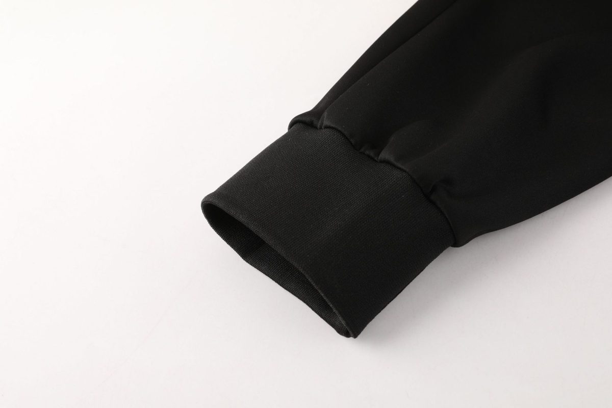 Close-up of a black fabric sleeve cuff with a stitched edge against a light background