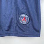 Close-up of blue fabric with a round Paris Saint-Germain patch stitched on.