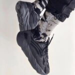 Dark gray chunky sneakers worn with a black-and-white patterned sock, shown in a tilted photo venue