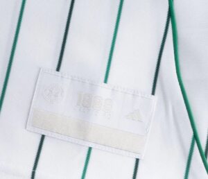 Close-up of a white soccer jersey with green vertical stripes and a white patch displaying 1988 and the Adidas logo