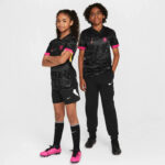 8e3912cf_0cc3_4e9e_b3cc_2c8b8bea88a5 | UAE SPORT STORE Two girls in matching black Nike soccer outfits stand side by side, pink accents on sleeves and shoes, Ready for practice or a game.
