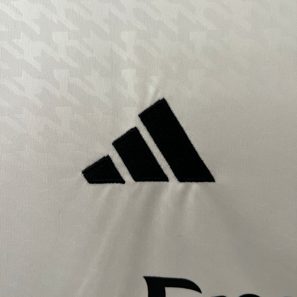 Close-up of a light gray knit fabric with a bold black diagonal stripe/pattern at the bottom edge.