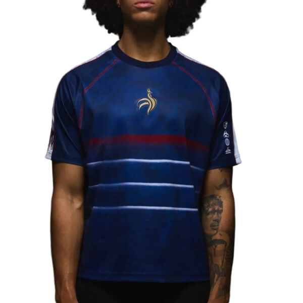 Person wearing a dark blue athletic jersey with a gold emblem on the chest and red trim details on the shoulders and sleeves.