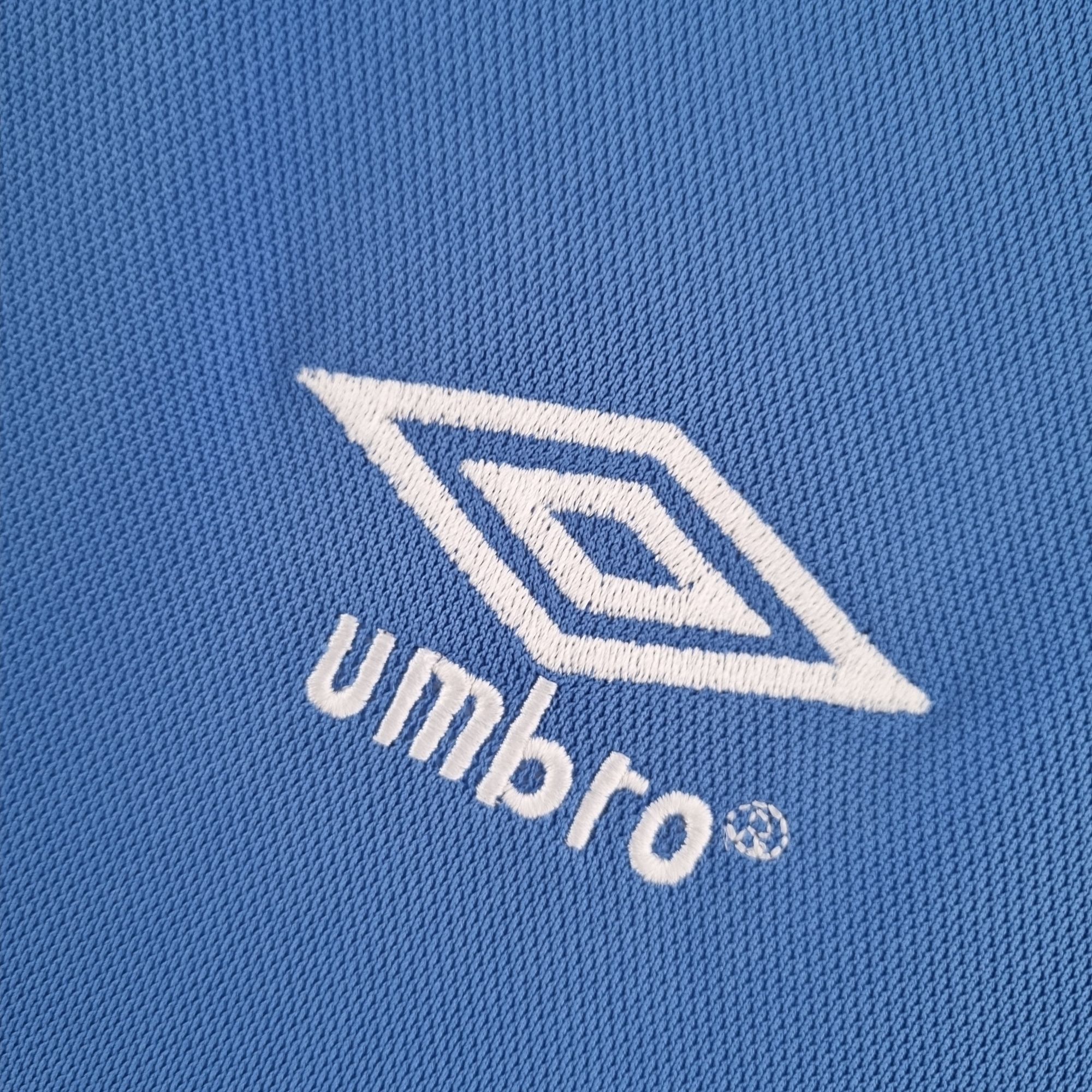 8ebc3e65_7804fdf0-da54-417f-992f-bf20a89014e5 | UAE SPORT STORE Close-up of blue denim fabric featuring white stitched logo element curved across the material
