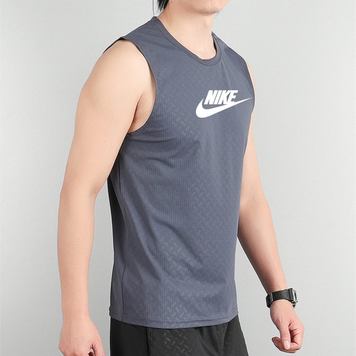Person wearing a gray sleeveless Nike top with a white swoosh logo on the chest beside the shoulder.
