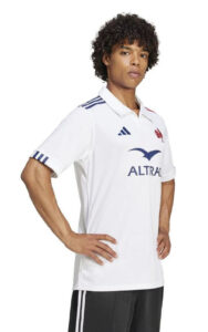 8f1da11d1136f30676c3116bb757bd1e | UAE SPORT STORE Male model wearing a white sports polo with blue accents, a blue bird logo and sponsor text on the chest.