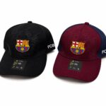 Two FC Barcelona caps, black and maroon, each with the club crest on the front and 'FCB' on the side.