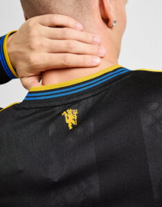 Back view of a person wearing a black athletic jersey with blue and yellow striped collar, hand resting on the neck; small yellow crest on the upper back.