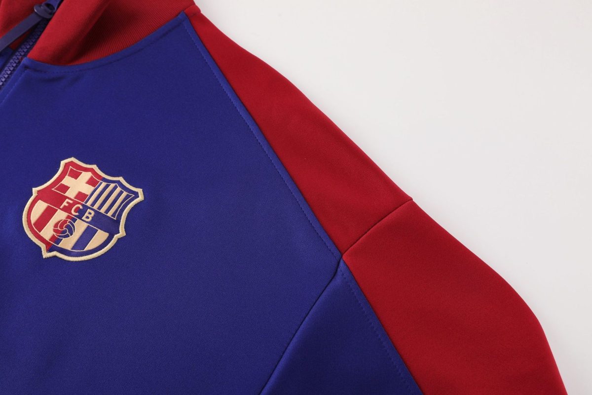 Close-up of a blue sports jersey with a red sleeve and an embroidered FC Barcelona crest in the lower left corner.